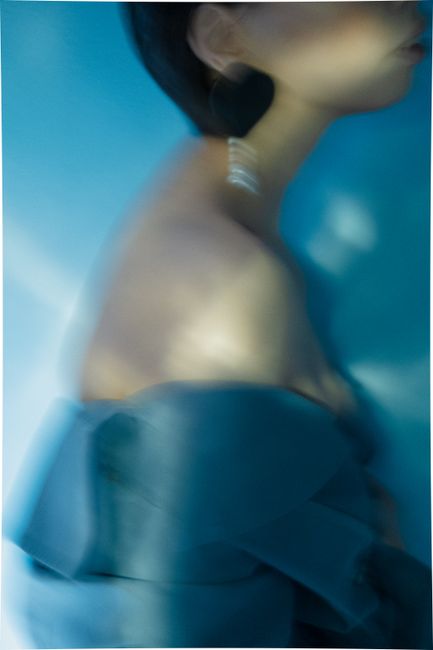 Blurred portrait of a woman in off-shoulder attire, highlighting elegance in blue tones.