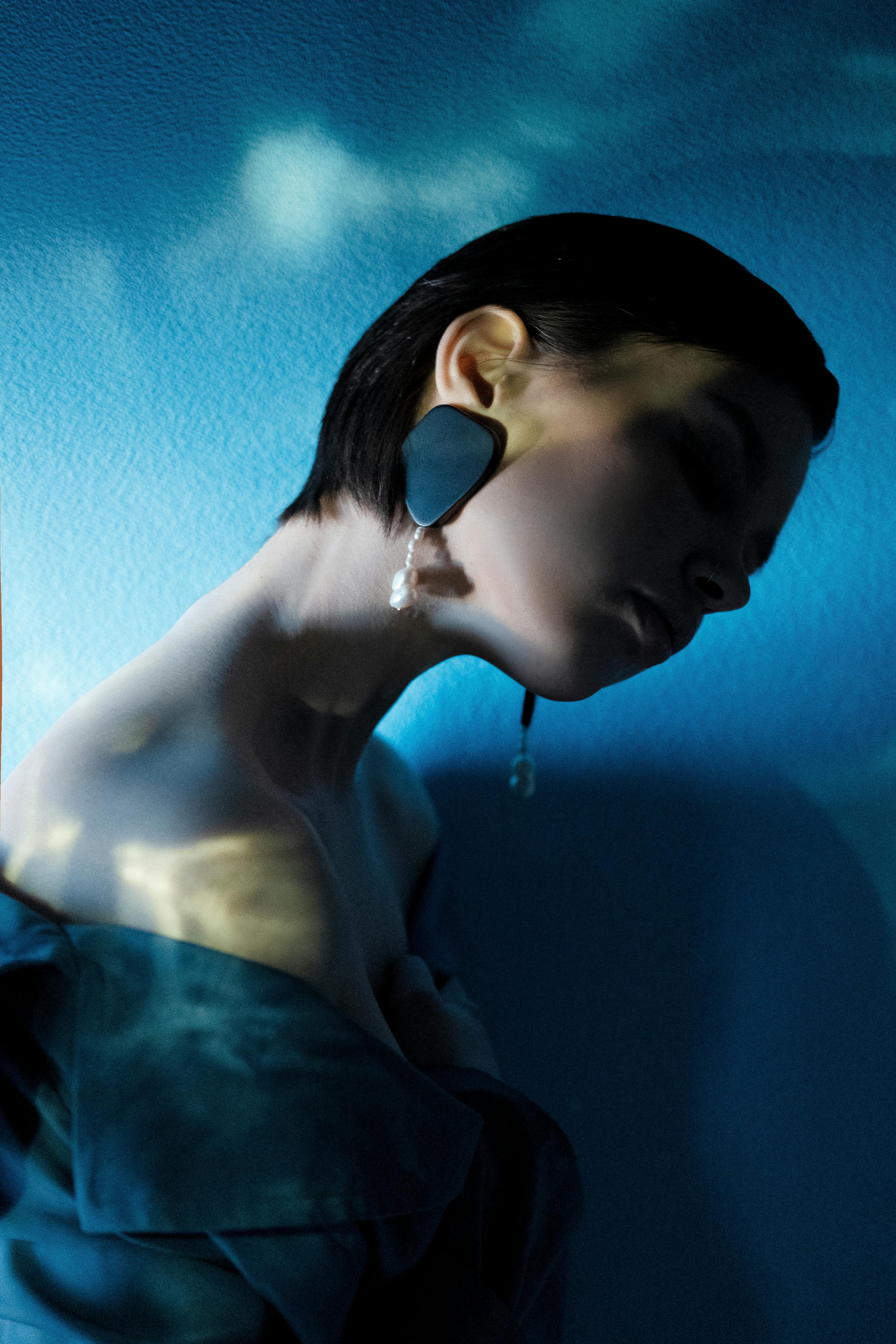 Artistic portrait of a woman with short hair and striking blue lighting.