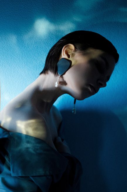 Artistic portrait of a woman with short hair and striking blue lighting.