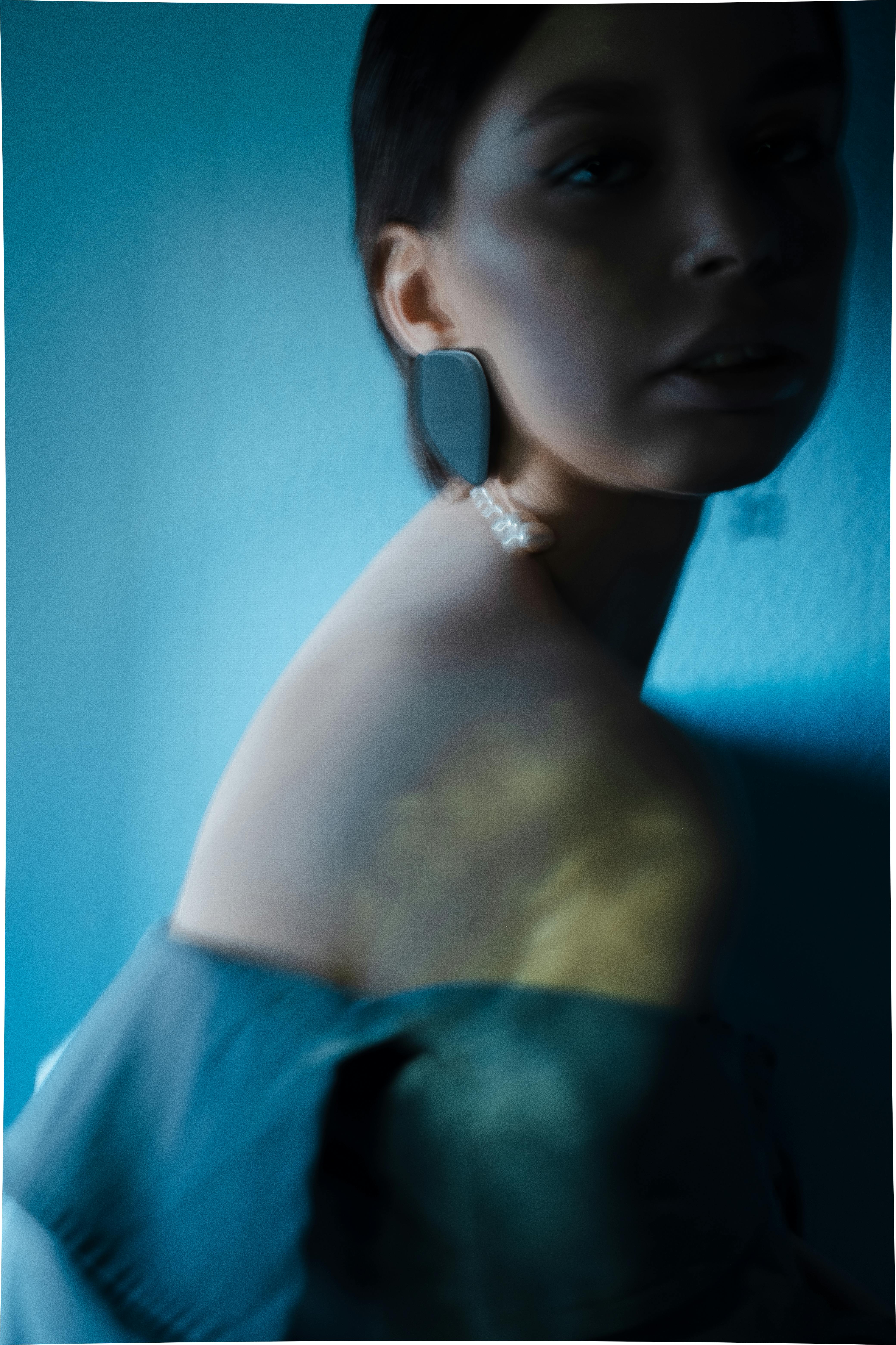Artistic portrait of a woman with an elegant, blurred style and a blue hue.