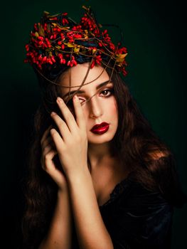 A striking portrait of a woman with an artistic red headdress, embodying elegance and mystery.