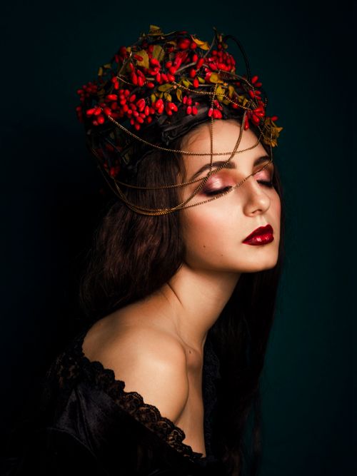 Free Elegant portrait of a woman with closed eyes, wearing an intricate floral headdress with vibrant red berries. Stock Photo