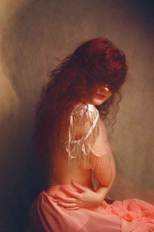 A Sultry Topless Woman Sitting with Hair Covering her Eyes 