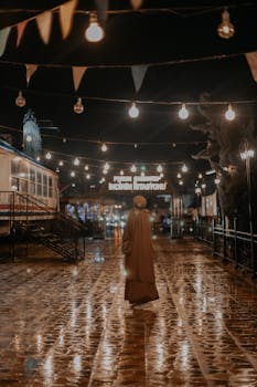 Person in abaya walks at night under colorful lights in an urban area, creating a reflective atmosphere.