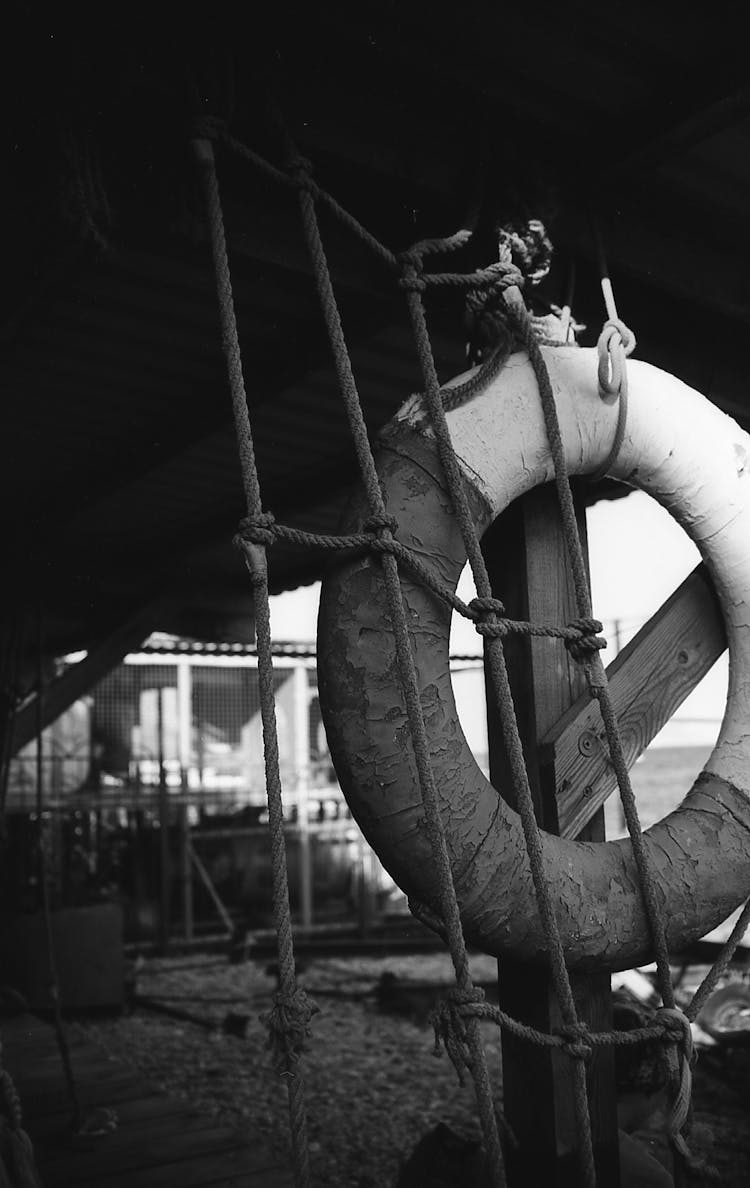 Grayscale Photo Of A Lifesaver Near A Rope