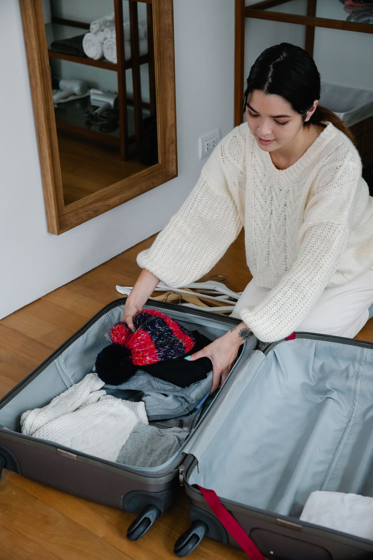 Woman packing clothes into a suitcase, preparing for travel. High angle view indoors.