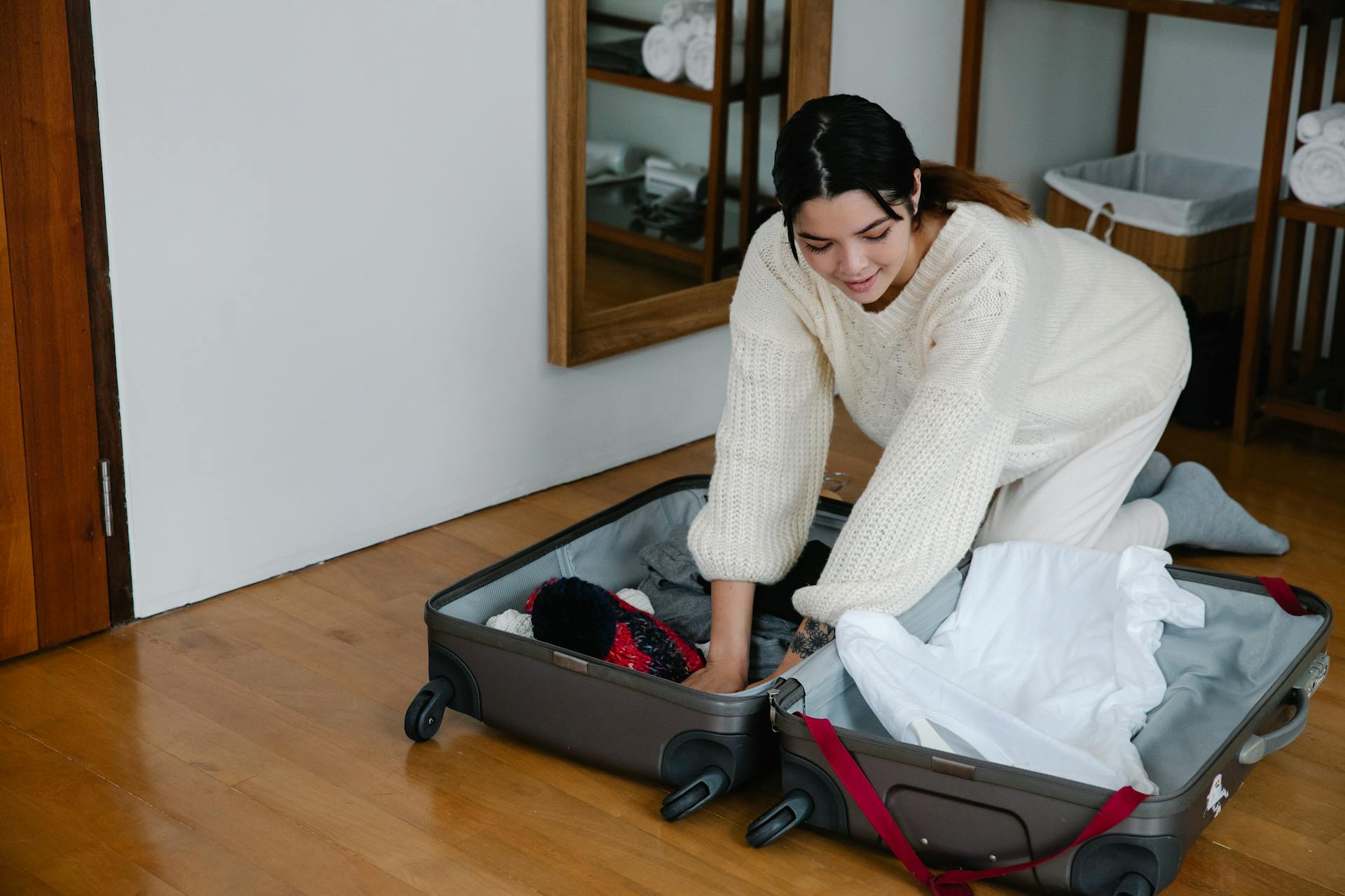 Woman in White Sweater Packing Clothes in the Luggage Bag