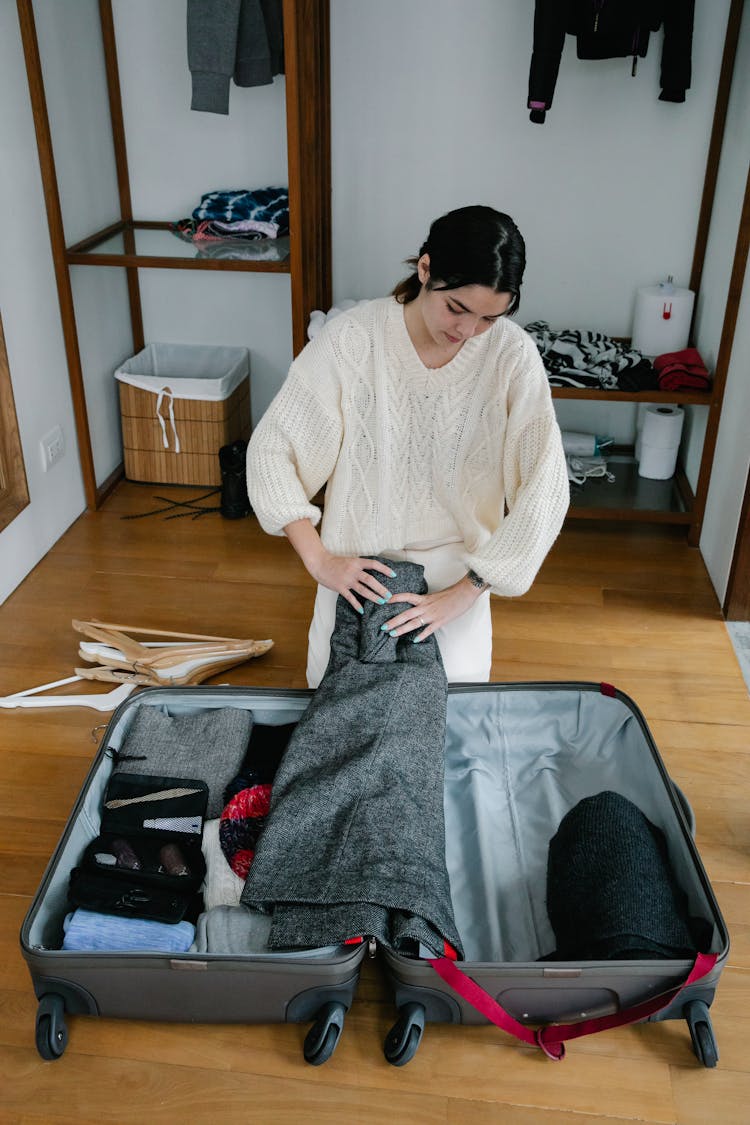 Woman In White Sweater Folding Clothes