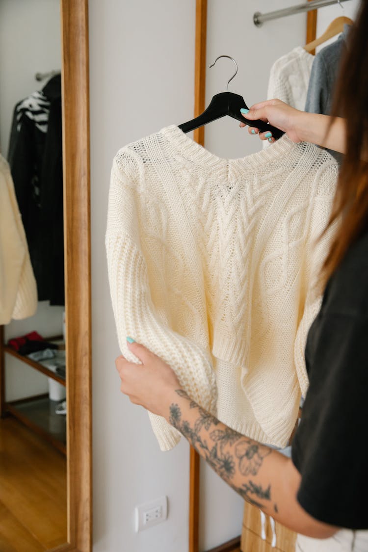 Person Holding Black Hanger With White Knitwear