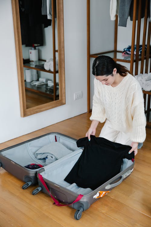 A Woman in Knitted Sweater Fixing Her Luggage