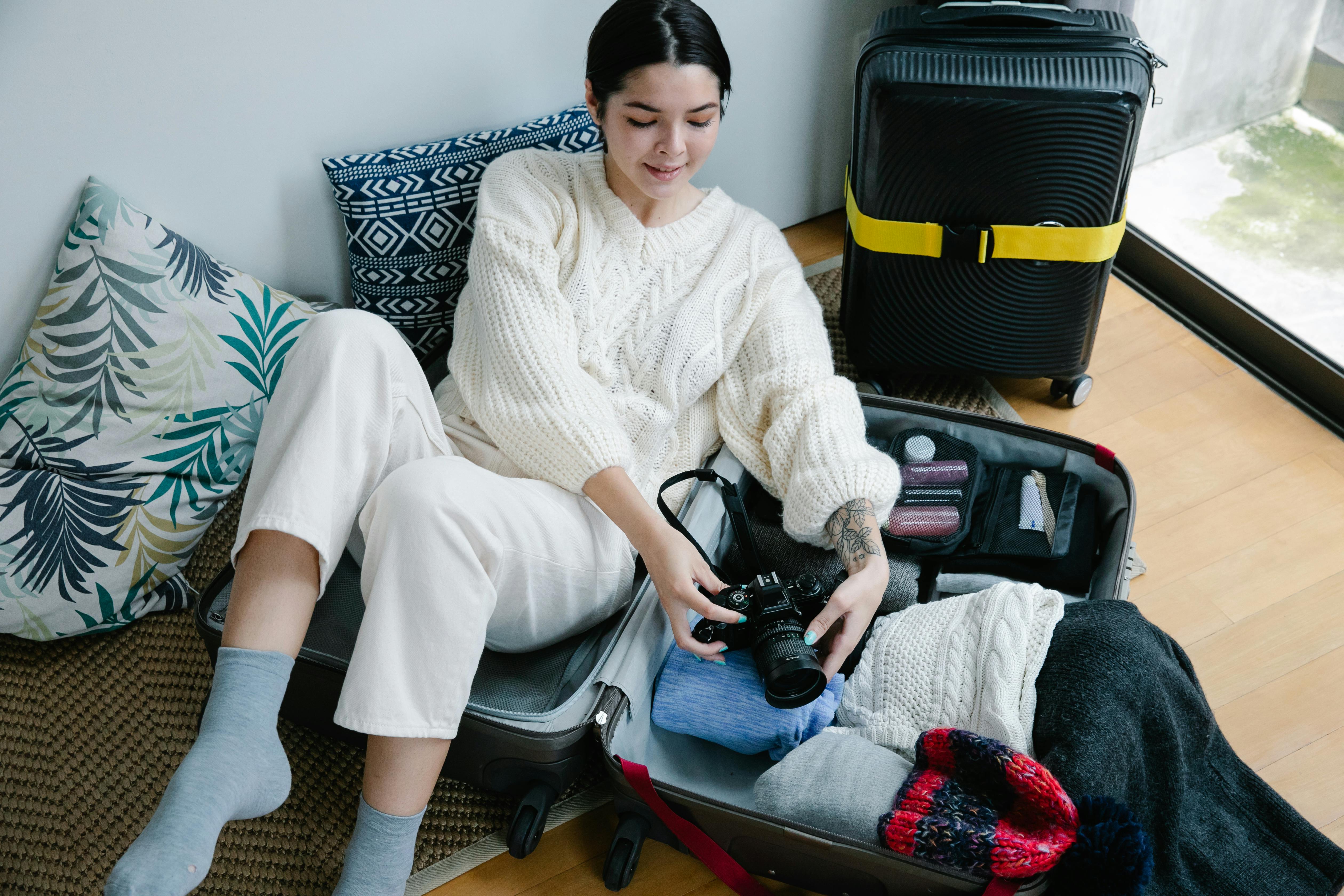 woman sitting on luggage holding black camera