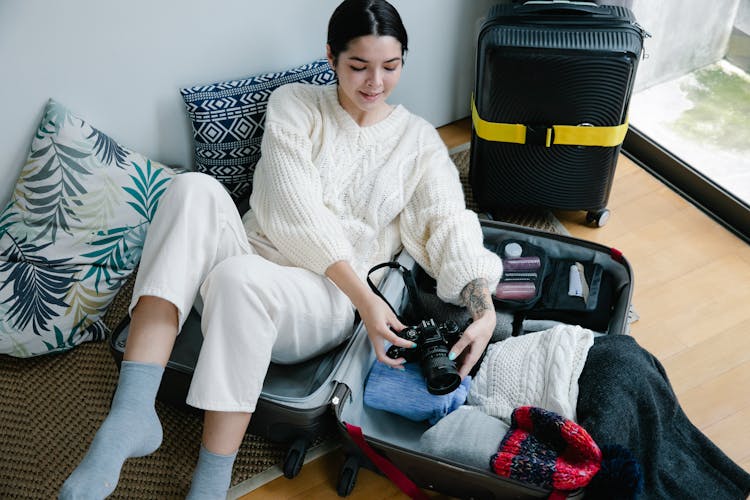 Woman Sitting On Luggage Holding Black Camera