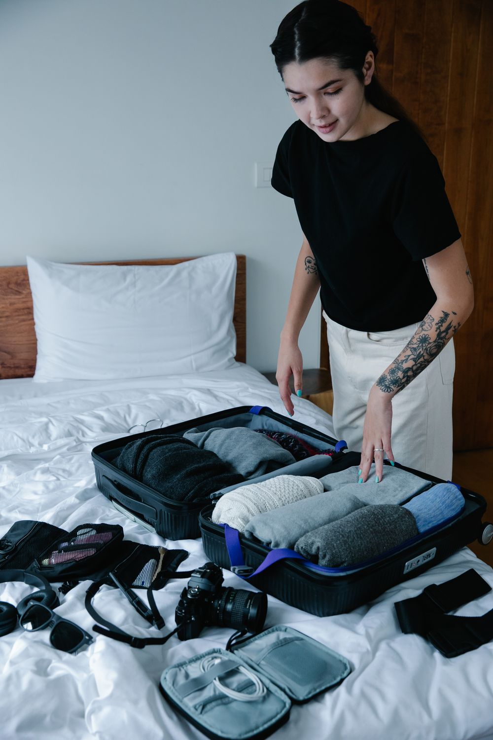 Photographer: Timur Weber Woman packing neatly organized suitcase on bed preparing for travel