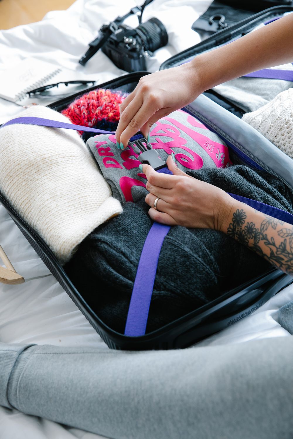 Woman carefully folding and packing winter clothing into a suitcase