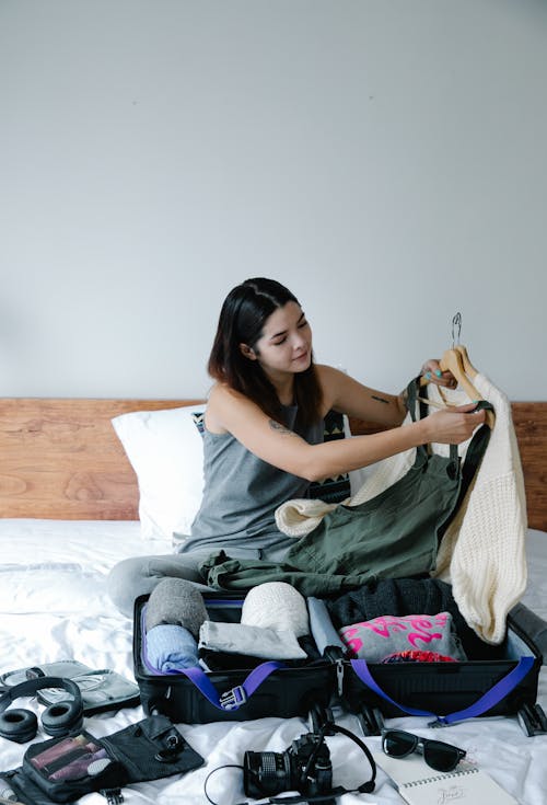 Woman Sitting on Bed While Packing Up