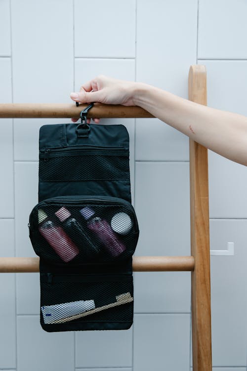 Free A Person Hanging a Travel Pouch on a Wooden Rack Stock Photo