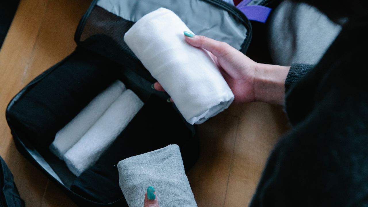 Folding clothes for efficient travel packing Person folding travel clothes into a suitcase using an organized packing method