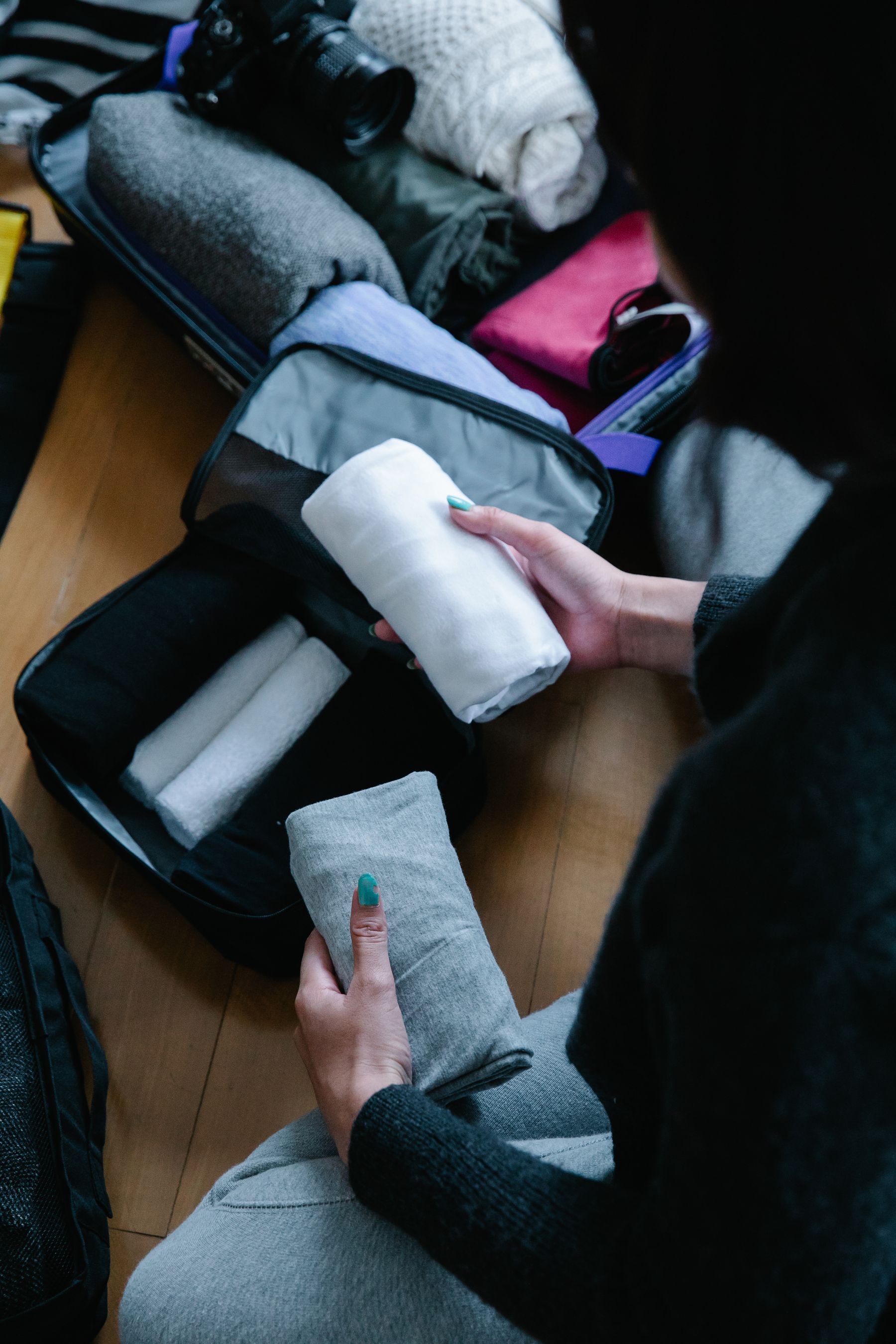 Person organizing folded clothing inside an open travel suitcase