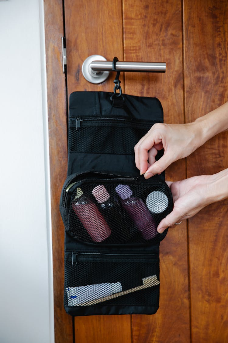 Person Zipping A Travel Bag With Cosmetic Products 