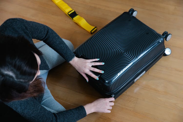 A Woman Zipping Her Luggage