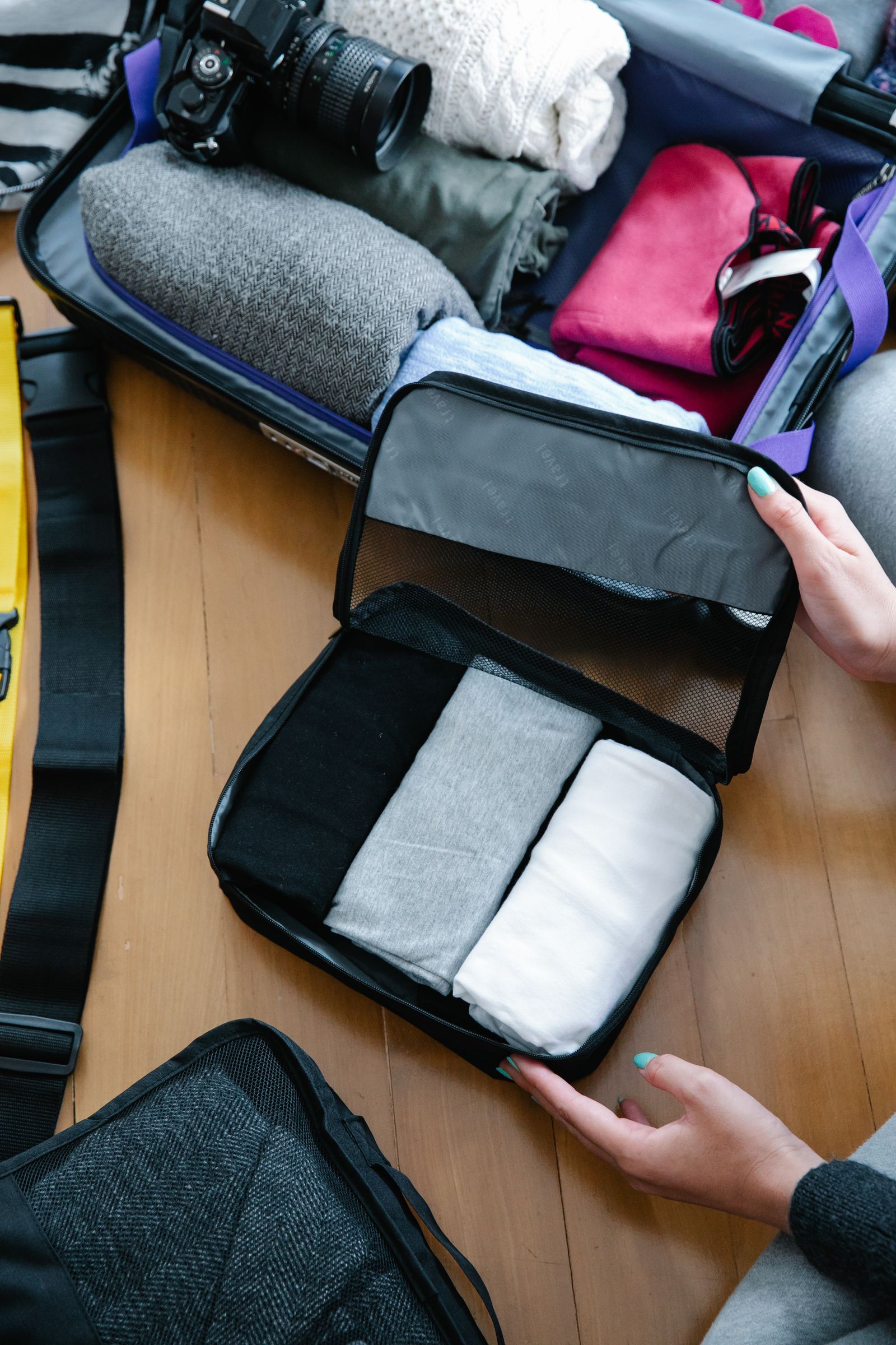 Traveler organizing clothing and travel essentials inside luggage