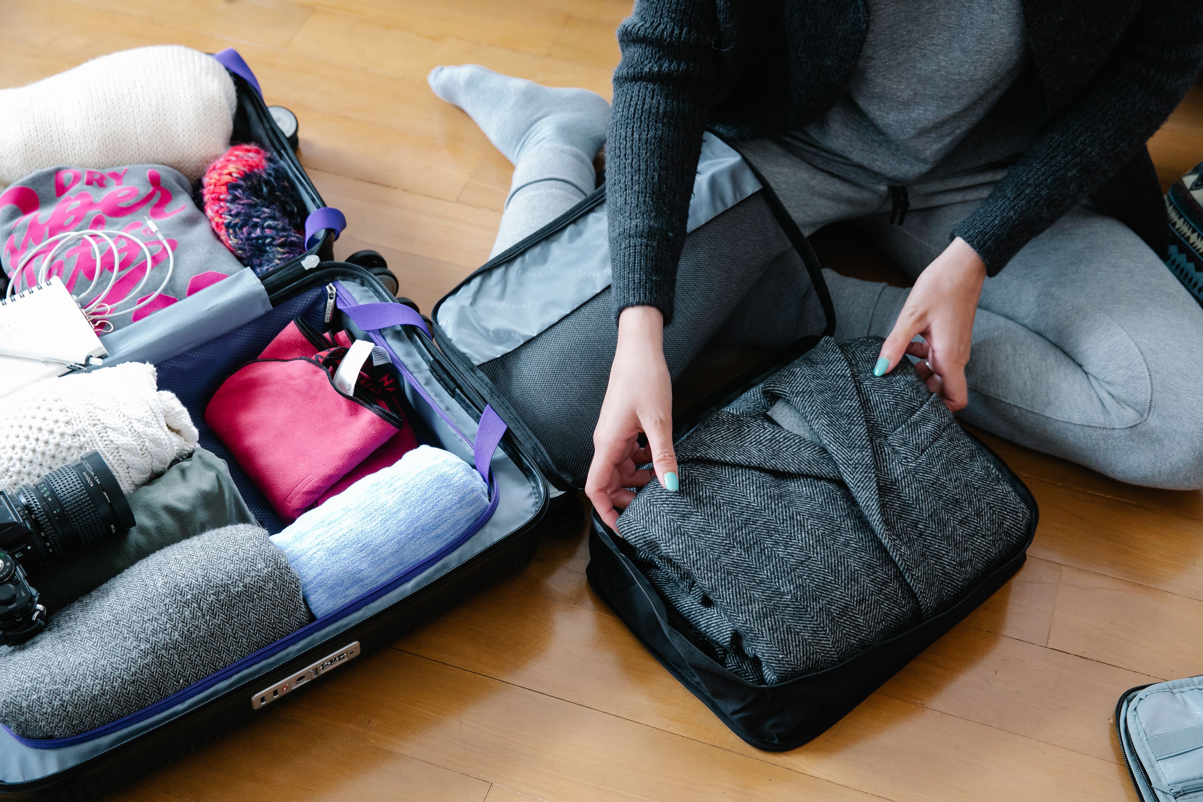 Matériel photo et vêtements rangés dans une valise avec des cubes de rangement avant un départ