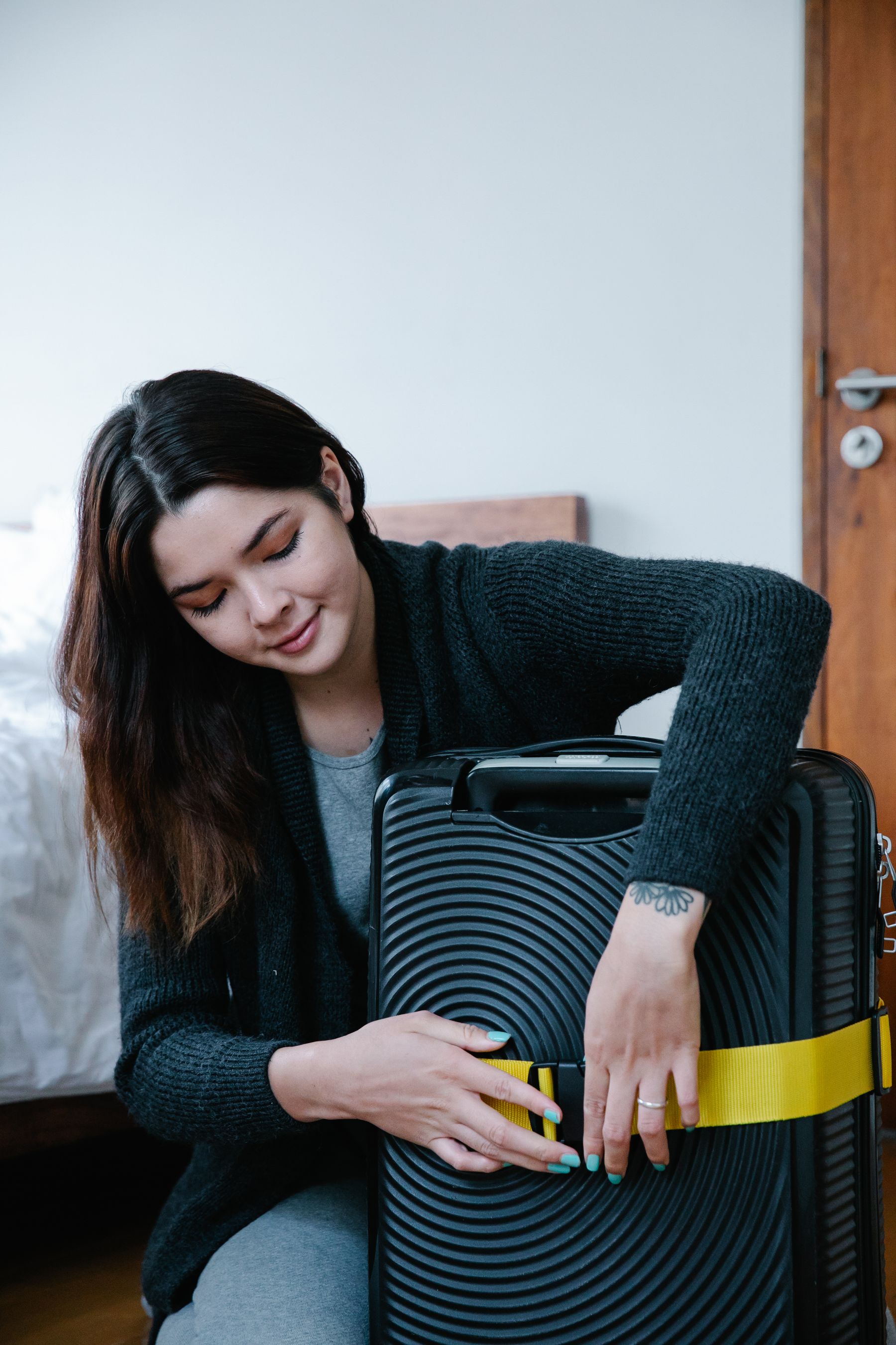 Traveler inspecting and securing the exterior of a hard shell rolling suitcase