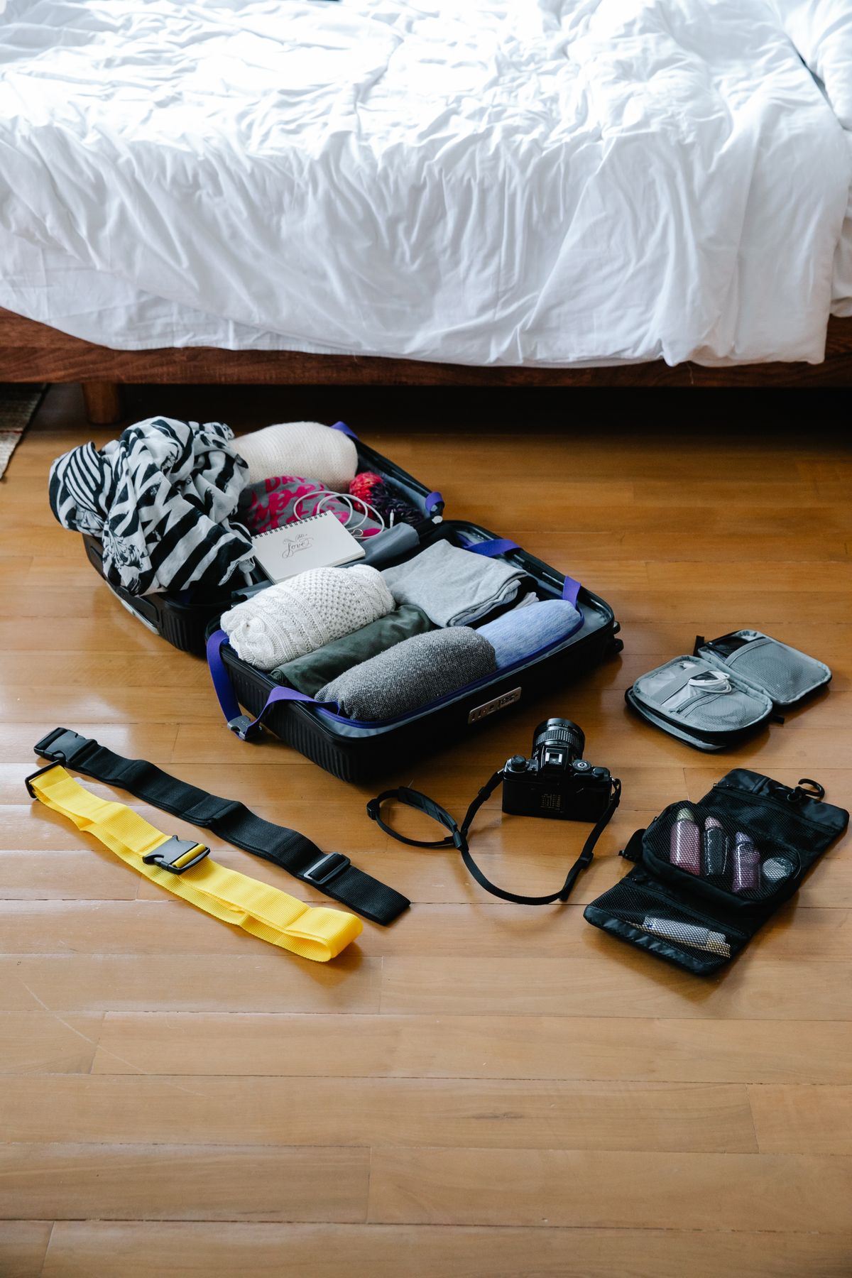 Flat lay of luggage and travel essentials on a wooden floor before a trip