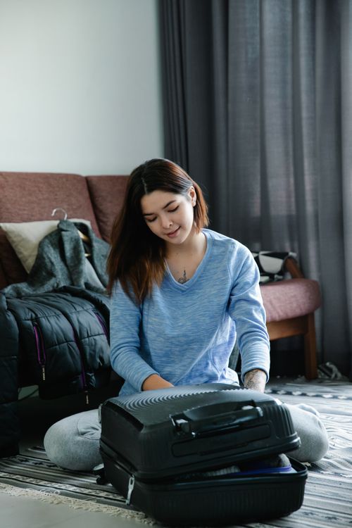 Free Smiling woman packing suitcase in cozy room, preparing for travel. Stock Photo