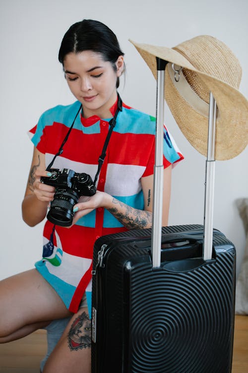Free A Woman Holding Her Camera Near Her Luggage Stock Photo