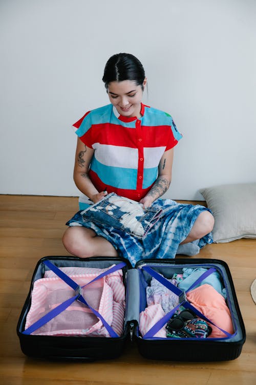 Free A Woman Sitting while Organizing Her Luggage Stock Photo