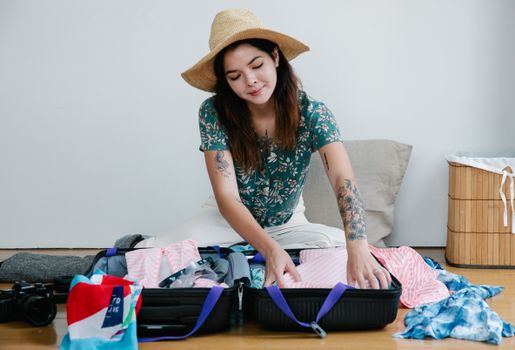 Woman packing suitcase for vacation, preparing for a trip.