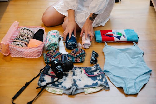 Free A Person Sitting on a Wooden Floor while Preparing Travel Essentials Stock Photo