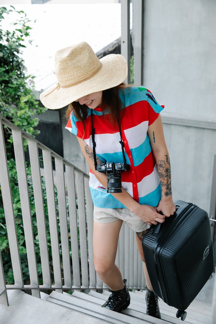 A Woman Walking Up The Stairs Carrying A Suitcase 