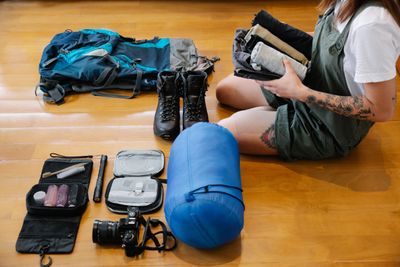 A traveller sorting packed clothes and gear on a wooden floor — photo by Timur Weber on Pexels