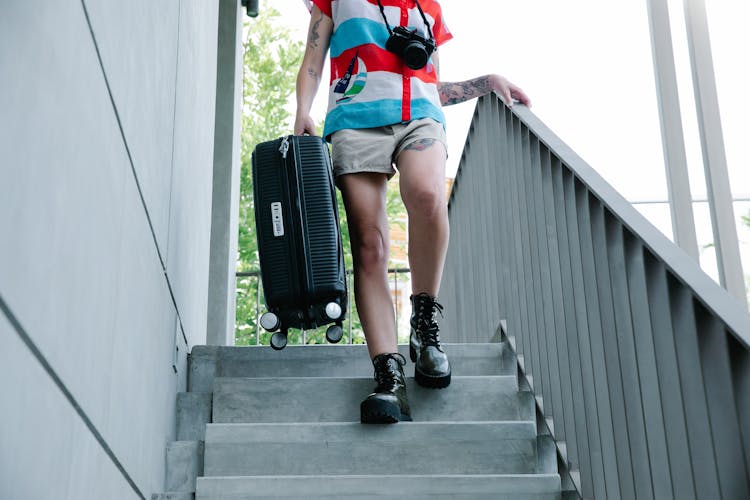 Low Section Of A Woman Walking Down Steps With A Suitcase In Hand