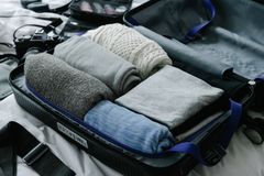 Open suitcase filled with neatly folded clothes on bed, ready for travel preparation.
