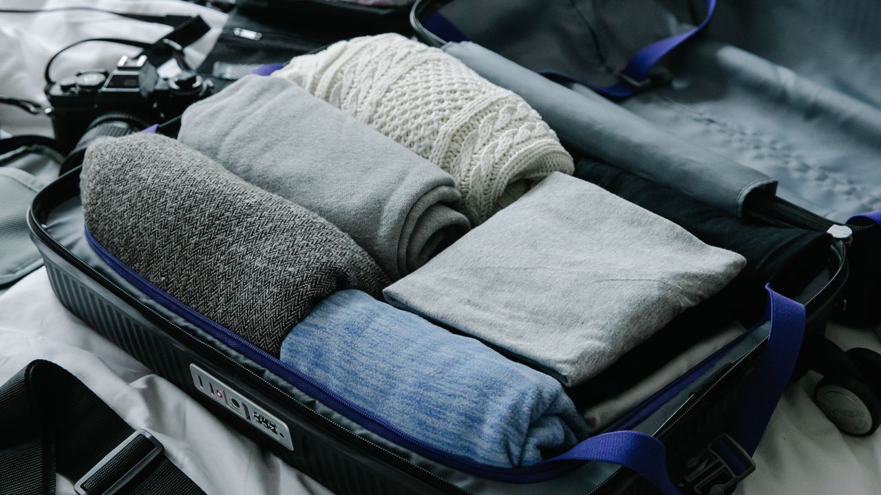 Minimal travel wardrobe packed in suitcase Open suitcase with folded clothing for a compact travel wardrobe