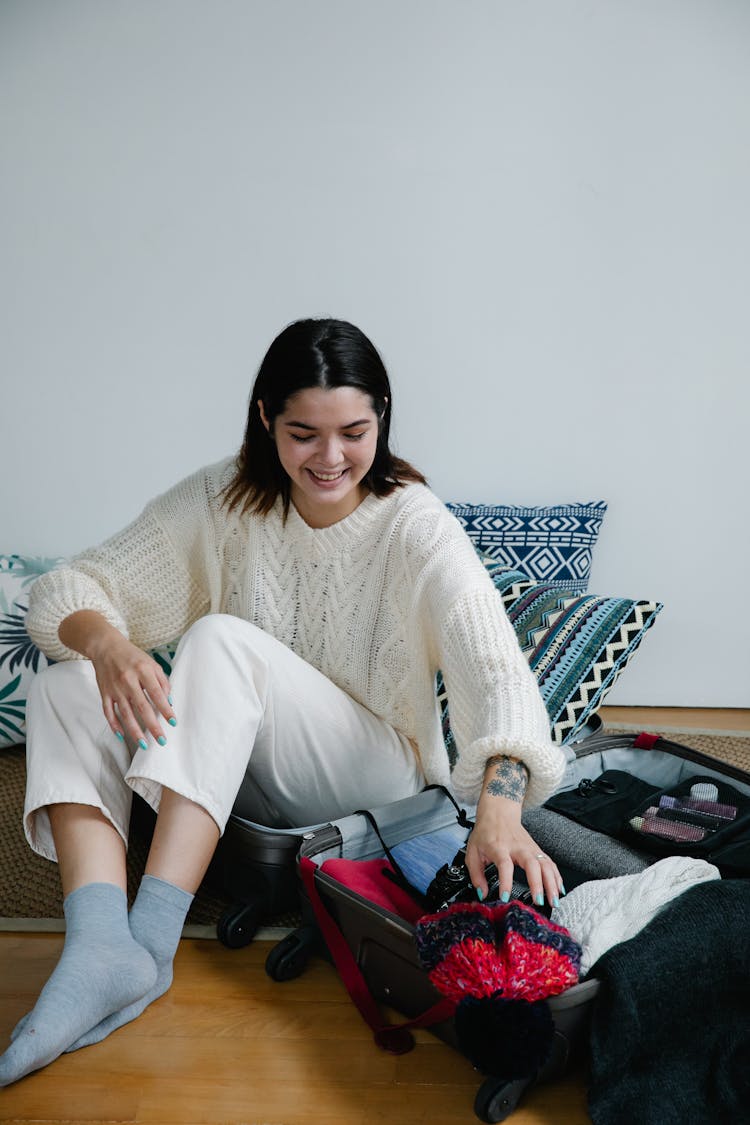 Smiling Woman Sitting In Suitcase Packing For Travel