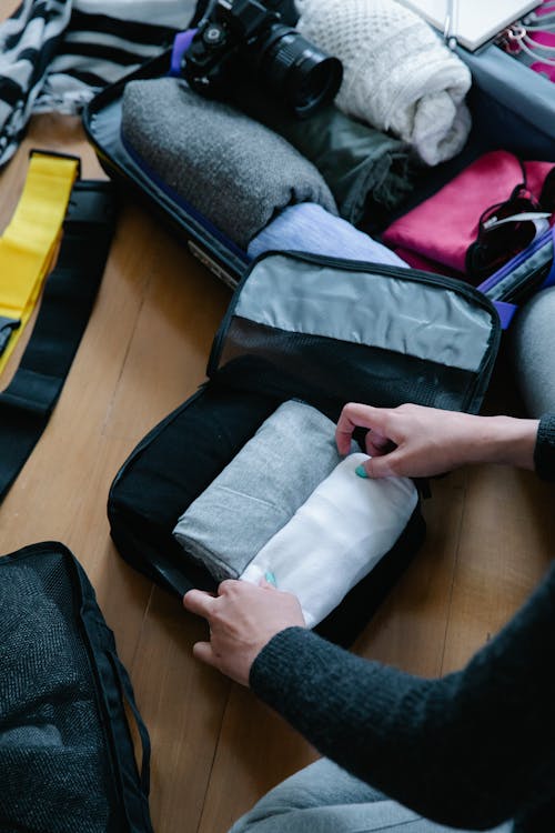 Free A Person Putting Folded Clothes on Pouch Stock Photo