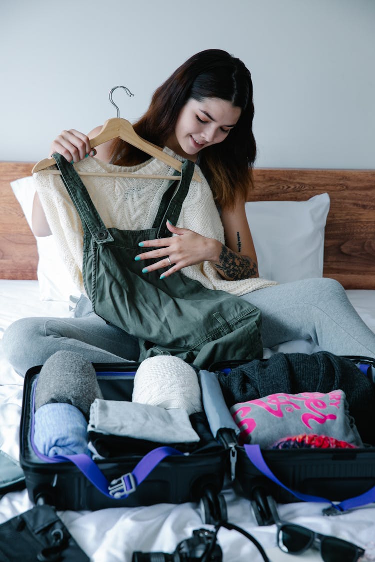 Woman Sitting On Bed Holding Clothes