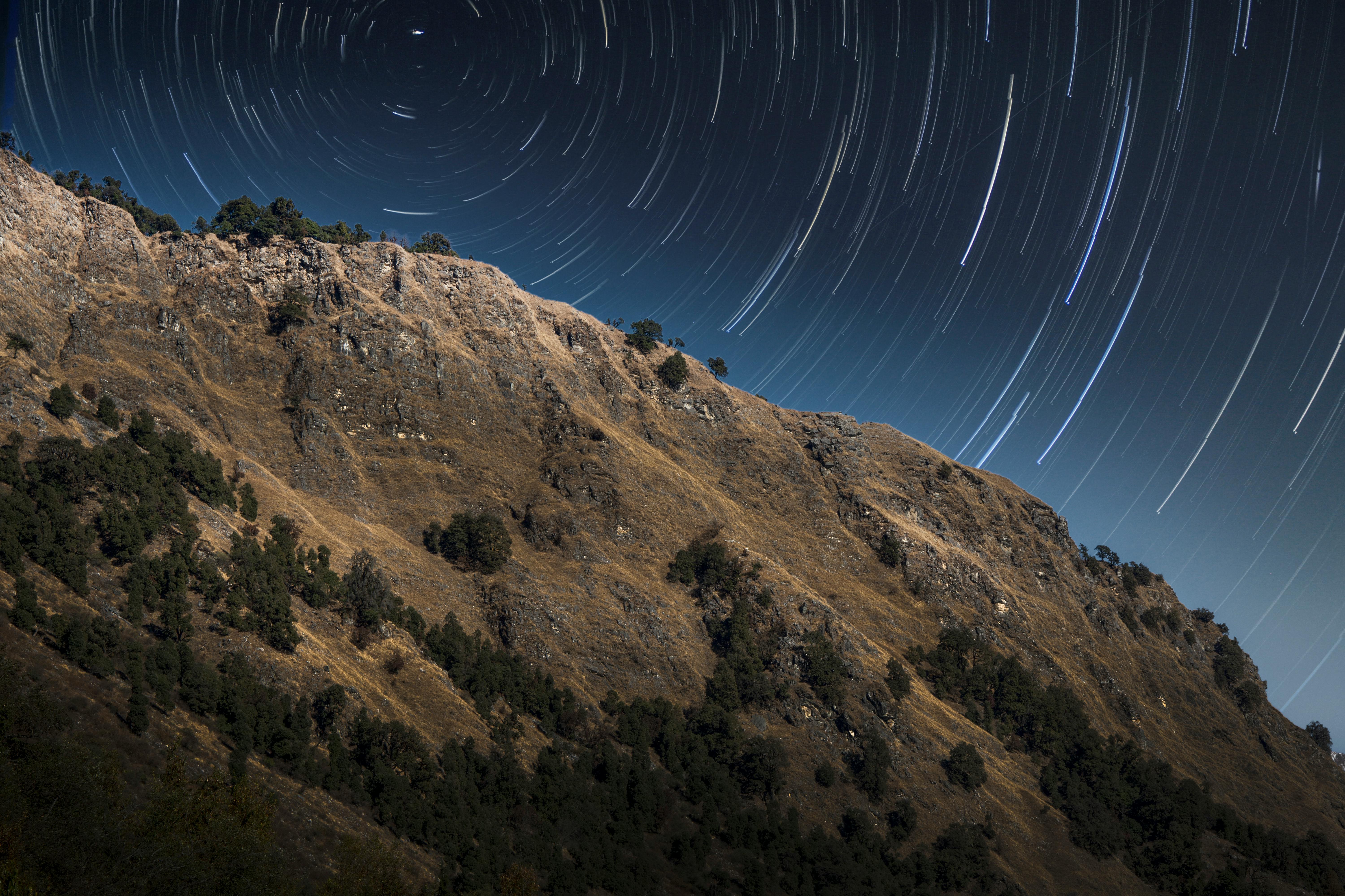 Stunning star trails over a rocky mountain landscape in Uttarakhand, India.