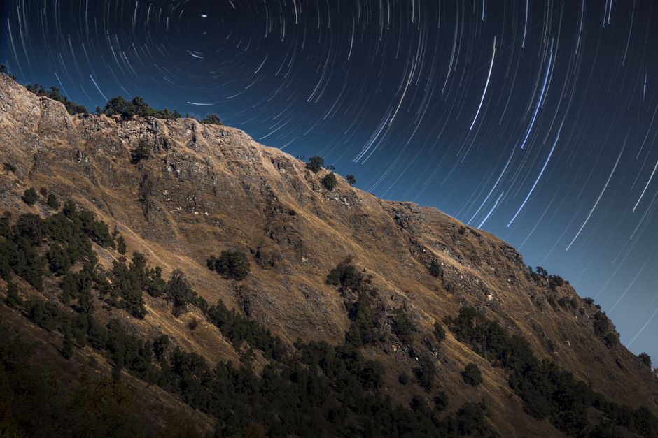 Stunning star trails over a rocky mountain landscape in Uttarakhand, India.
