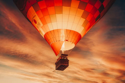 A White and Orange Hot Air Balloon in Mid Air Under Sunset Sky