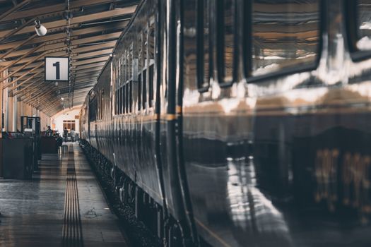 A classic train at an empty railway platform, with a warm and moody atmosphere.