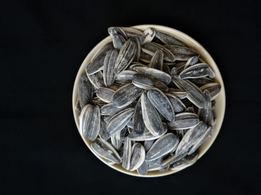 Bowl of sunflower seeds on a black background, perfect for healthy food themes.
