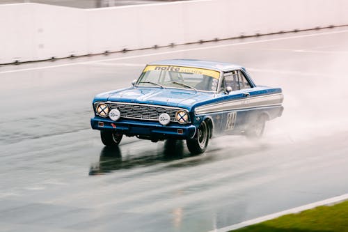 A Blue Ford Racing Truck Running Fast on a Wet Road