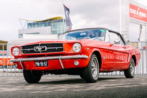 Free A Classic Red Ford Mustang Parked Near a Fence Stock Photo