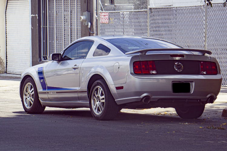 A Silver Grand Tourer Car Parked Outside A Steel Wire Gate