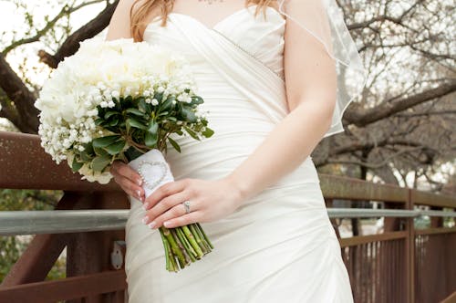 Женщина в белом свадебном платье с цветами в руках